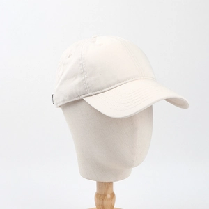 Detail view of a beige cotton baseball cap with reinforced stitching on the brim