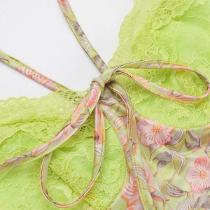 Gros plan sur la dentelle vert clair et la bretelle en satin fleuri nouée en un joli nœud