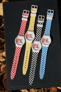 Detail of four colorful checkerboard quartz watches with silicon straps on a dark book