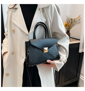 Détail du sac à main noir à motif crocodile avec boucle dorée et bandoulière amovible