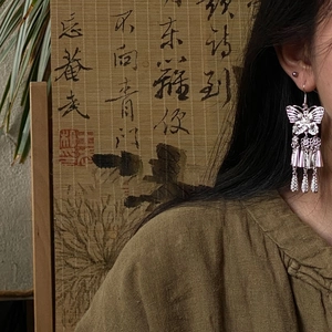 Detail of silver hollow butterfly tassel earrings worn, showing ethnic retro style