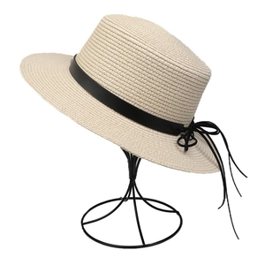 Detailed macro view of the beige woven straw texture and black ribbon bow on the sun hat