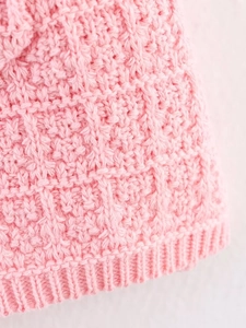 Close-up of pink chunky knit fabric showing detailed weaving and texture of the dress