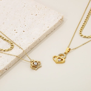 Close-up of gold plated layered necklace with crown and heart pendants with zircons