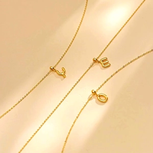 Gold bubble letter pendant necklaces with initials Y, E, and O on delicate cross chains