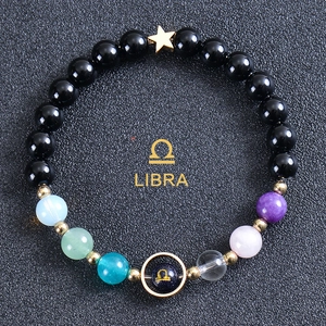 Macro detail of Libra zodiac bracelet with black beads, colorful stones and star pendant