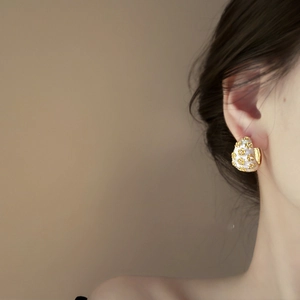 Detail of vintage white enamel C-shape hoop earring with golden floral pattern