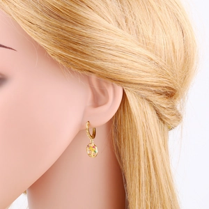 Close-up of golden hoop earrings with colorful gemstones and tree of life design