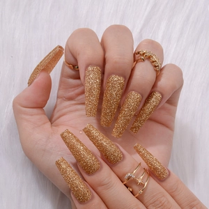 Close-up of long coffin glitter golden press-on nails on a soft white plush background