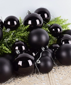 Detail of glossy and matte black Christmas baubles on pine branches with silver caps