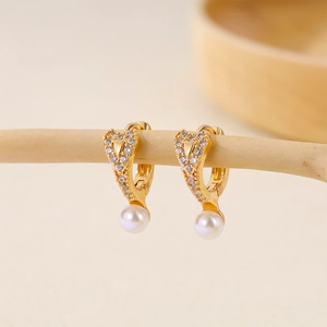 Macro shot of gold-plated heart-shaped pearl earrings featuring micro-pave cubic zirconia