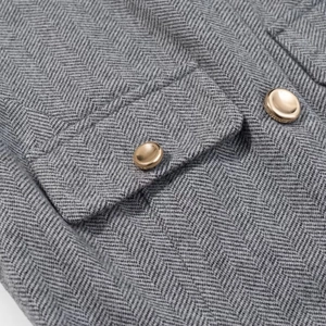 Détail du tissu à chevrons gris avec rabat de poche et boutons en métal doré
