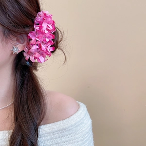 Detail of a large rose-pink fabric flower hair clip styled on a model's brown hair