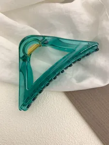 Detail of transparent green triangular hair claw clip with golden metal spring and grip