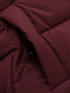 Detailed macro view of side pocket with metal snap button on burgundy quilted jacket