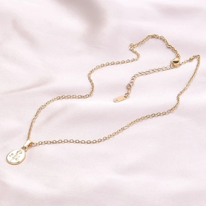 Close-up of golden oval rose embossed pendant on soft pink satin fabric background