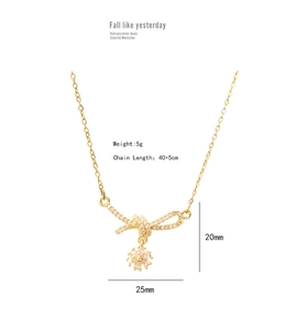 Detailed view of gold bow pendant with white crystals and floral drop measuring 25x20mm