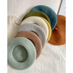 Close-up of thick wool berets in various colors arranged on a white textured cloth