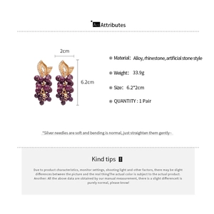 Vue détaillée de boucles d'oreilles raisin violet avec feuilles dorées et strass