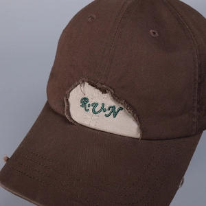 Close-up of distressed vintage baseball cap featuring embroidered letters and ripped detail