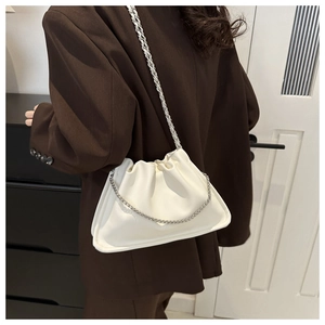 White ruched cloud shoulder bag with silver chain strap worn over a brown blazer
