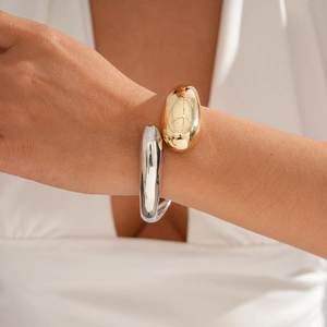 Close-up of minimalist gold and silver organic geometric crossover open bangles on wrist