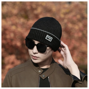 Detail of winter knitted beanie with brand tag, gray stripes and warm fleece lining