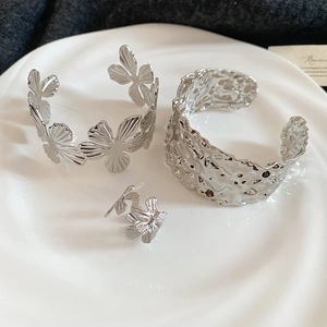 Detailed macro view of silver flower bracelet and hammered texture bangle set in a white tray