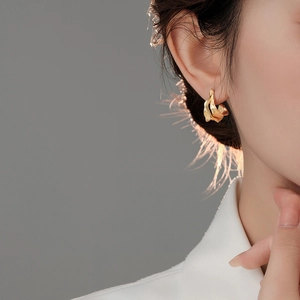 Macro detail of golden abstract irregular textured earring on female model with soft lighting
