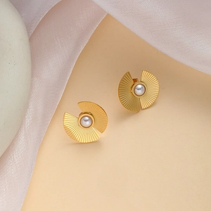 Detail of elegant gold fan-shaped stud earrings with center white pearl on satin