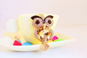 Close-up of golden owl keychain with crystal wings and champagne heart-shaped gemstone
