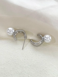 Vue macro de la boucle d'oreille en argent S925 avec perle blanche et métal