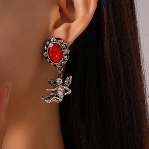 Close-up of retro silver earrings with red oval gemstones and cupid angel pendants