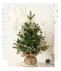 Close-up of decorative mini Christmas tree with LED lights and burlap base on a white desk