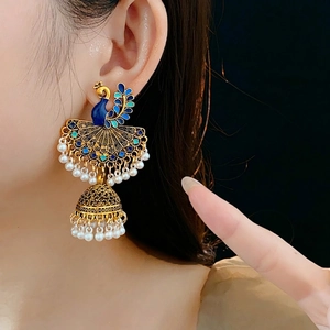 Vintage peacock tassel earrings with blue enamel and pearls on a model side view