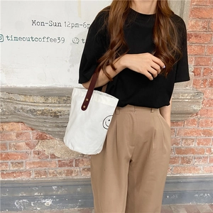 Polka dot canvas bucket bag with leather handle shown in a lifestyle street fashion view