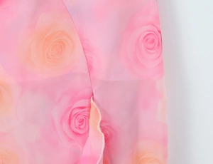 Detailed close-up of pink rose print chiffon fabric with delicate ruffled edge stitching