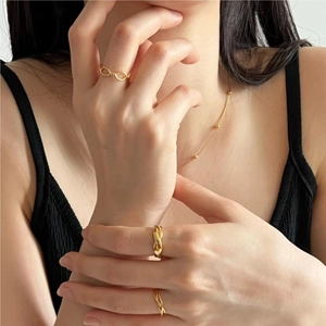 Close-up of minimalist 925 silver twisted rings and dainty gold necklace on a model