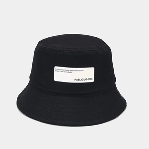 Detail of black cotton bucket hat with white rectangular text patch and classic brim