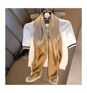 Detail of silk-like striped scarf in gold and white draped over a casual outfit