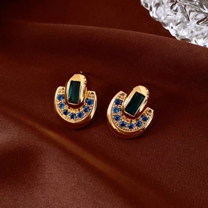 Macro de boucles d'oreilles ovales plaquées or 18K avec pierre émeraude sur soie rouge