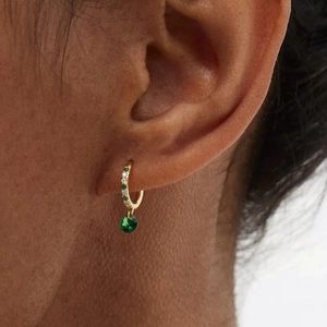 Detailed close-up of S925 sterling silver emerald earrings worn on a female ear model