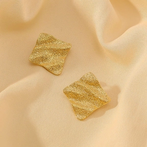 Textured 18k gold plated stainless steel wave earrings on elegant beige silk background