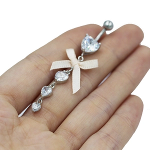 Piercing de nombril à la mode avec zircon en cœur et nœud en tissu beige sur main