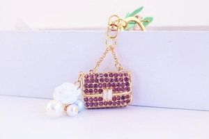 Macro view of purple rhinestone purse keychain with resin rose and pearl detail