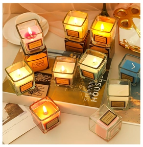 Close-up of burning colorful scented glass candles with glowing flames in cozy interior