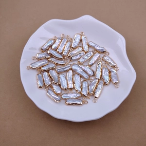 Close-up of white baroque pearls with gold loops in a ceramic bowl for DIY jewelry