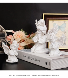 Detailed view of three white resin praying angel sculptures with floral wreaths