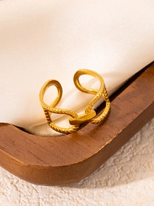 Close-up of golden adjustable twisted rope ring with knot detail on silk fabric