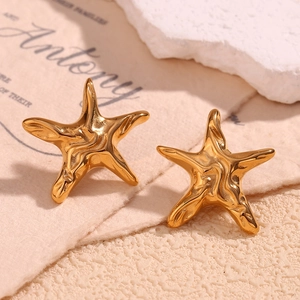 Macro shot of gold starfish earrings with irregular texture on mineral stone background